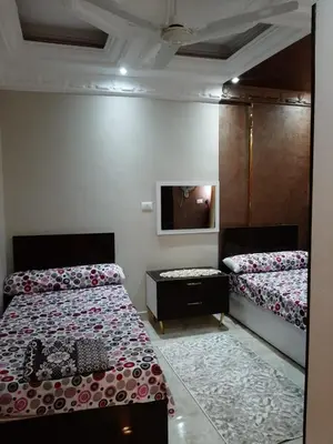 a bedroom with two beds and a tv on the wall at Horus Heights in Idfu