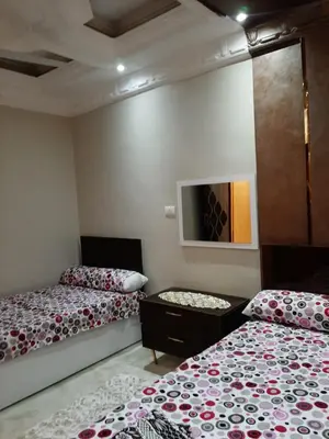 a bedroom with two beds and a tv on the wall at Horus Heights in Idfu