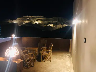 a patio with a table and chairs at night at Tarteel Apartment in Luxor