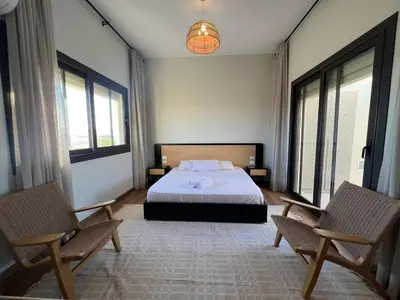 a bedroom with a bed and two chairs at Bohemian-Style 3BR Townhouse in Shedwan, El Gouna. in Hurghada