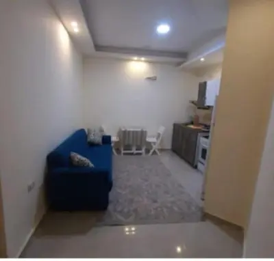 a living room with a blue couch and a kitchen at Casablanca Beach Appartment in Hurghada