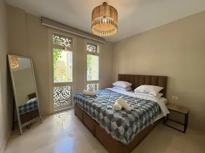 a bedroom with a bed and a mirror and a chandelier at Cozy 1BR GF Mangroovy Residence in Hurghada