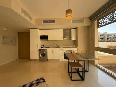a kitchen with white cabinets and a table and a window at Cozy 1BR GF Mangroovy Residence in Hurghada