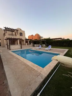 a swimming pool with two chairs and a house at Exclusive Villa in Sabina • 4 BR • Private Pool in Hurghada
