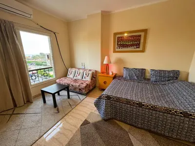 a bedroom with a bed and a chair and a window at Hurghada 201 in Hurghada