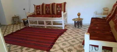 a living room with two beds and a rug at Desert studio in Al Aqālitah