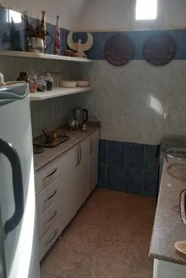 a kitchen with white cabinets and blue tiled walls at Desert studio in Al Aqālitah
