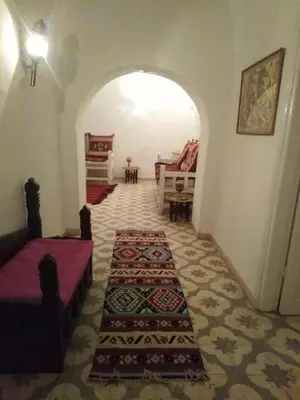 a room with an archway with a couch and a table at Desert studio in Al Aqālitah