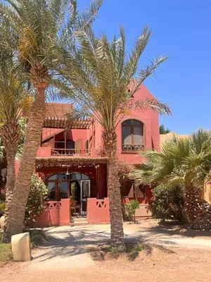 a pink house with palm trees in front of it at West Golf beautiful Townhouse in Hurghada