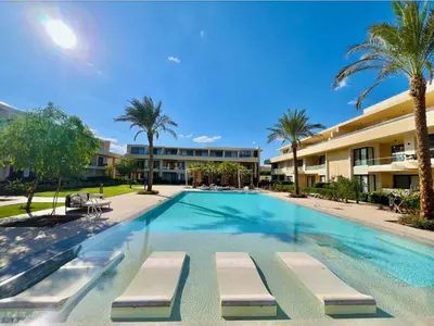a swimming pool with chaise lounges in front of a building at Cozy studio G-cribs elgouna in Hurghada