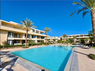 a swimming pool in front of a building with palm trees at Cozy studio G-cribs elgouna in Hurghada