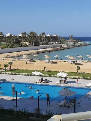 a large pool with people swimming in it next to a beach at luxury one bedroom at scandic resort in Hurghada