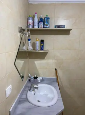 a bathroom with a sink and a shelf with bottles at Turtles beach resort in Hurghada