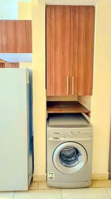 a washing machine in a kitchen with wooden cabinets at Decoraive Appartment AlDaU Hurghada in Sahl Hasheesh