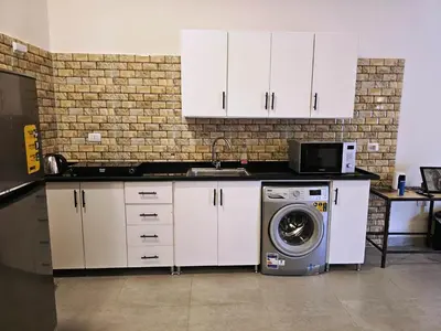 a kitchen with white cabinets and a washing machine at Malika House in Luxor