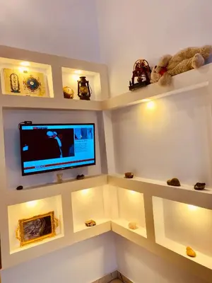a room with shelves with a flat screen tv at Alena guest house in Jazīrat al ‘Awwāmīyah