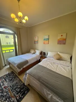 a bedroom with two beds and a chandelier at Sahl Hasheesh Finest Chalet - Gravity resort beachfront family 2 bedroom - garden pools view waterpark NON EGYPTIAN ONLY in Hurghada