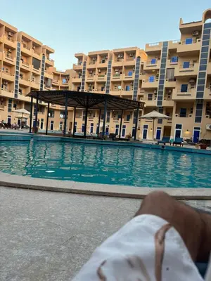 a person laying in front of a swimming pool in front of a building at El nour in Hurghada