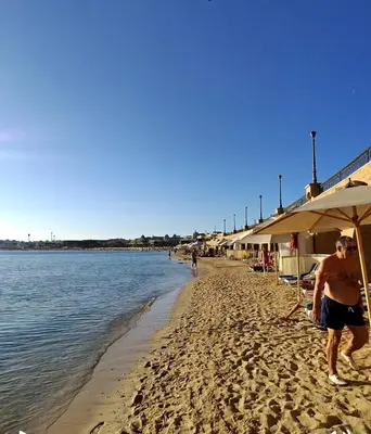 a man walking on a beach next to the water at Sunset Pearl APARTMENTS in Hurghada
