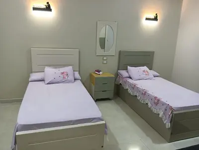 two beds in a bedroom with a mirror and lights at noreno guest house in Aswan