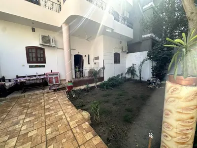 a large white house with a courtyard in front of it at Garden Level Oasis Near Nile in Luxor
