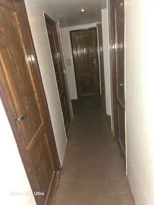 an empty hallway with wooden doors and carpet at The grand in Nag` el-Ramla
