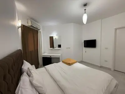 a white bedroom with a bed and a television at Regency Towers Apartments in Hurghada