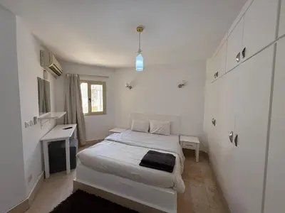 a white bedroom with a bed and a desk at Regency Towers Apartments in Hurghada