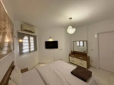 a white bedroom with a bed and a mirror at Regency Towers Apartments in Hurghada
