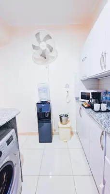a white kitchen with a dishwasher and a fan at Luxor Grand House in ‘Ezbet Abu Ḥabashi