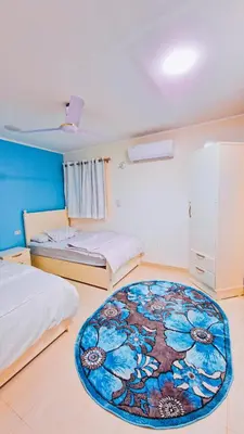a bedroom with two beds and a rug on the floor at Luxor Grand House in ‘Ezbet Abu Ḥabashi