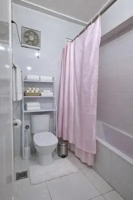 a bathroom with a toilet and a pink shower curtain at Luxor Grand House in ‘Ezbet Abu Ḥabashi