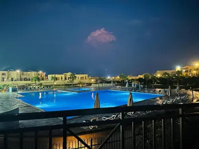 a large swimming pool at night with chairs and buildings at The View Hurghada in Hurghada