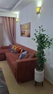 a brown couch in a living room with a potted plant at Palma chalet 169 in Hurghada