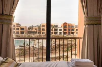 a bedroom with a view of the beach from a window at Posh Gouna Poolside in Hurghada