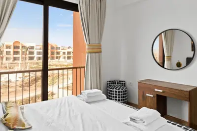 a bedroom with a bed and a mirror and a balcony at Posh Gouna Poolside in Hurghada