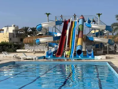 a boy is standing in front of a water slide at fanadir resort in Hurghada