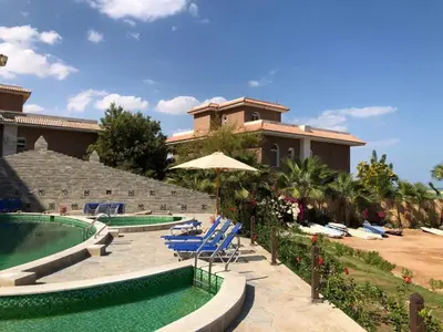 a resort with a pool and chairs and a building at Turtle beach resort in Hurghada