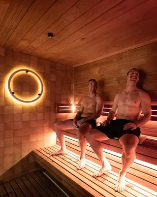 two men sitting on a bed in a sauna at NG Trips in Hurghada
