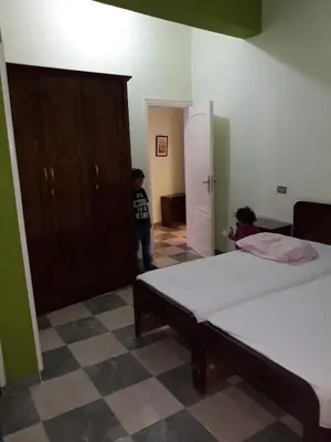 a boy standing in a room with two beds at Obelisk house in Luxor