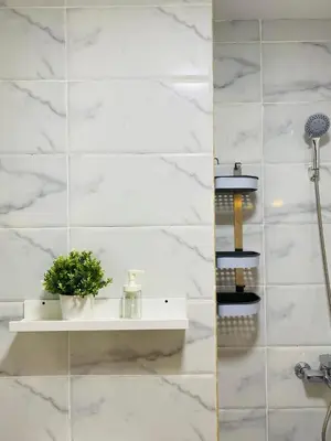 a white tiled bathroom with a shelf with a plant at Quiet, cozy resort apartment in Hurghada