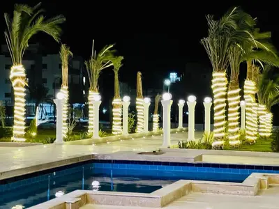 a pool at night with palm trees and lights at Quiet, cozy resort apartment in Hurghada
