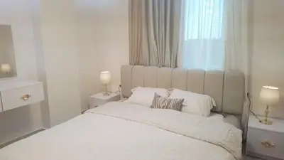 a white bedroom with a large bed with two lamps at Quiet, cozy resort apartment in Hurghada