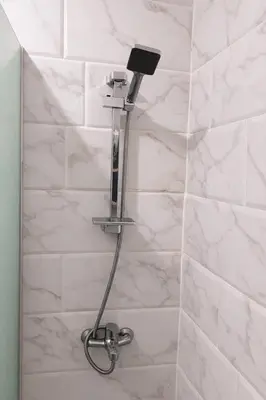 a shower with a light on a white tiled wall at stylish cozy one bedroom apartment in Hurghada