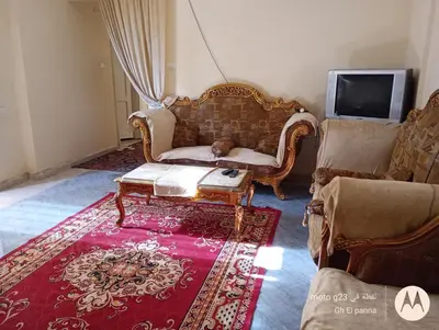 a living room with a couch and a red rug at بيت فرح in Nag` el-Fuqâhi