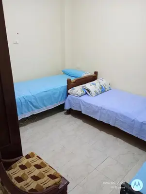 a room with two beds and a chair at بيت فرح in Nag` el-Fuqâhi