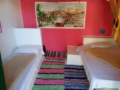 a room with two beds and a painting on the wall at فندق اجيليكا in Aswân Reservoir Colony