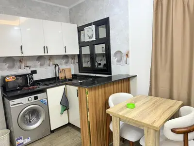 a kitchen with a washing machine and a table at VERO Residence in Banī Ghālib