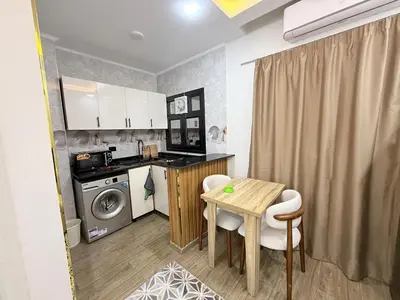 a small kitchen with a table and a washing machine at VERO Residence in Banī Ghālib