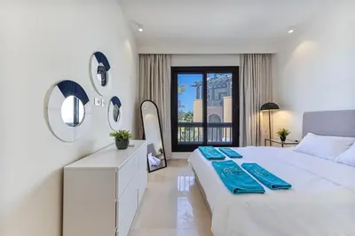a white bedroom with a large bed and a window at Dreamy gateway in Ancient Sands in Hurghada